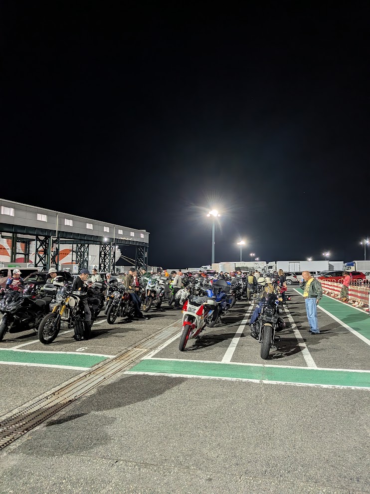 夜の大阪南港。照明の下にバイクがずらりと並び、ライダーが支度をしている