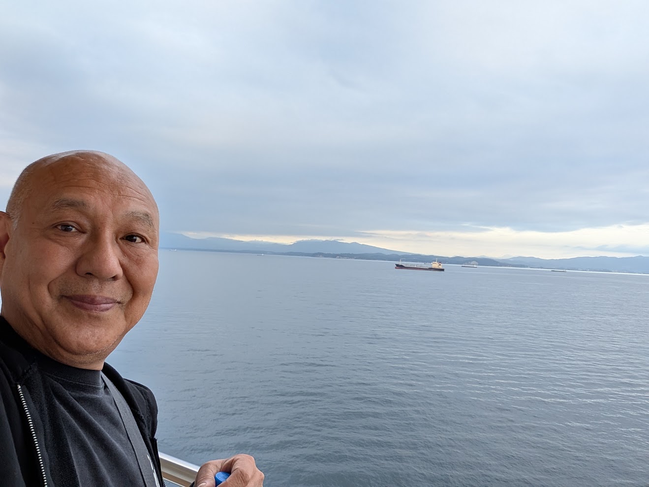 船の上から見た別府湾。貨物船が浮かび、向こうに山並みが見える