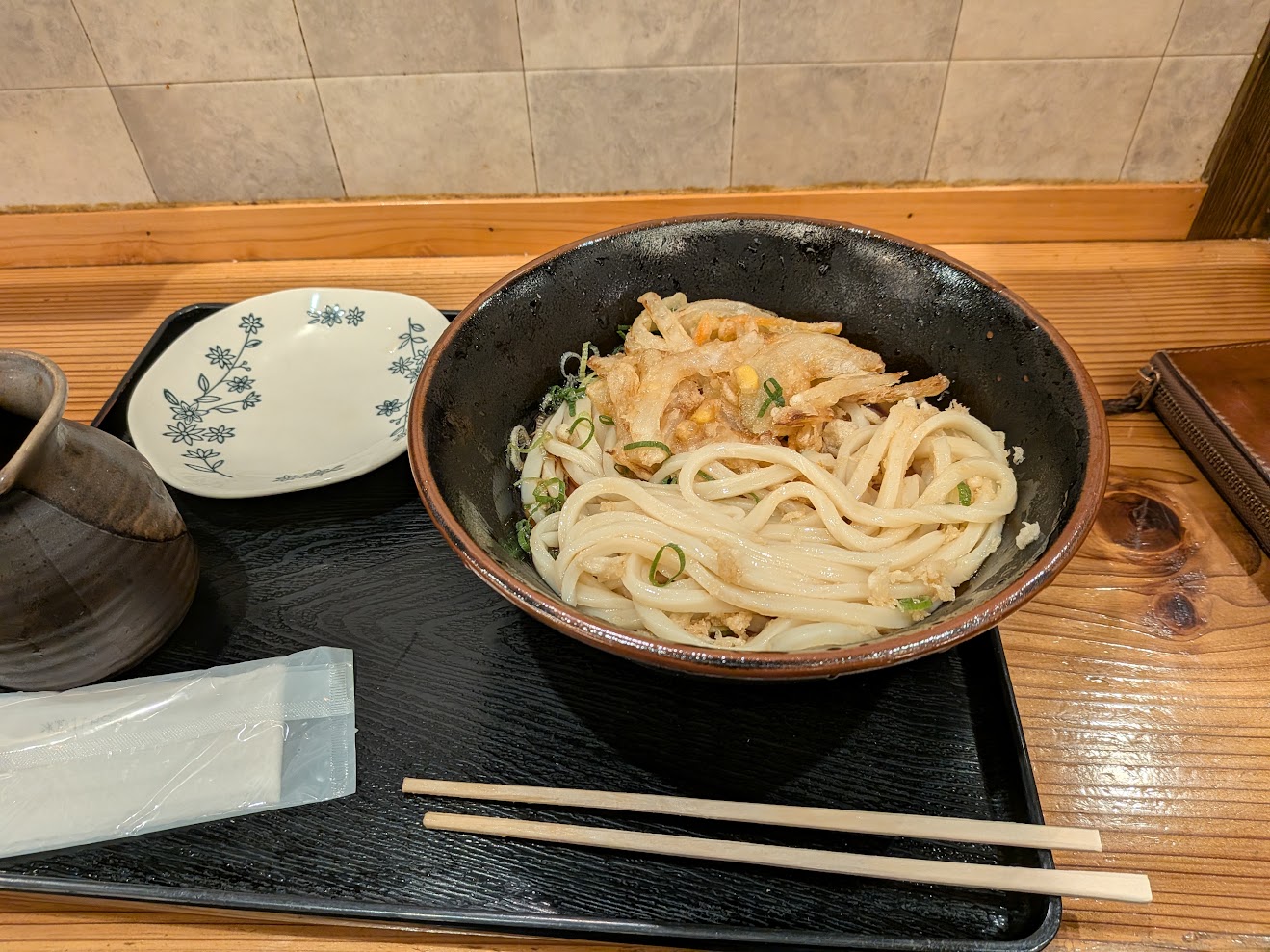 かき揚げの載ったうどんの丼が、カウンターのトレーに置いてある