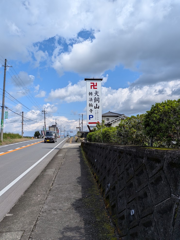 「犬飼山 轉法輪寺」と書かれた赤白の幟看板。青空